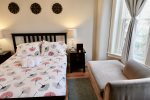 Primary bedroom includes a queen sized bed and a reading chaise, perfect for catching up with a good book